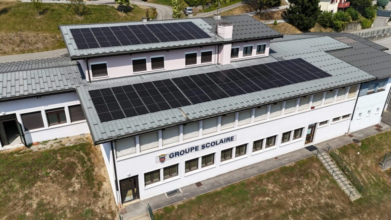 Prise de vue de drône d'un bâtiment scolaire équipé de panneaux solaire sur 2 pans de toiture exposé sud