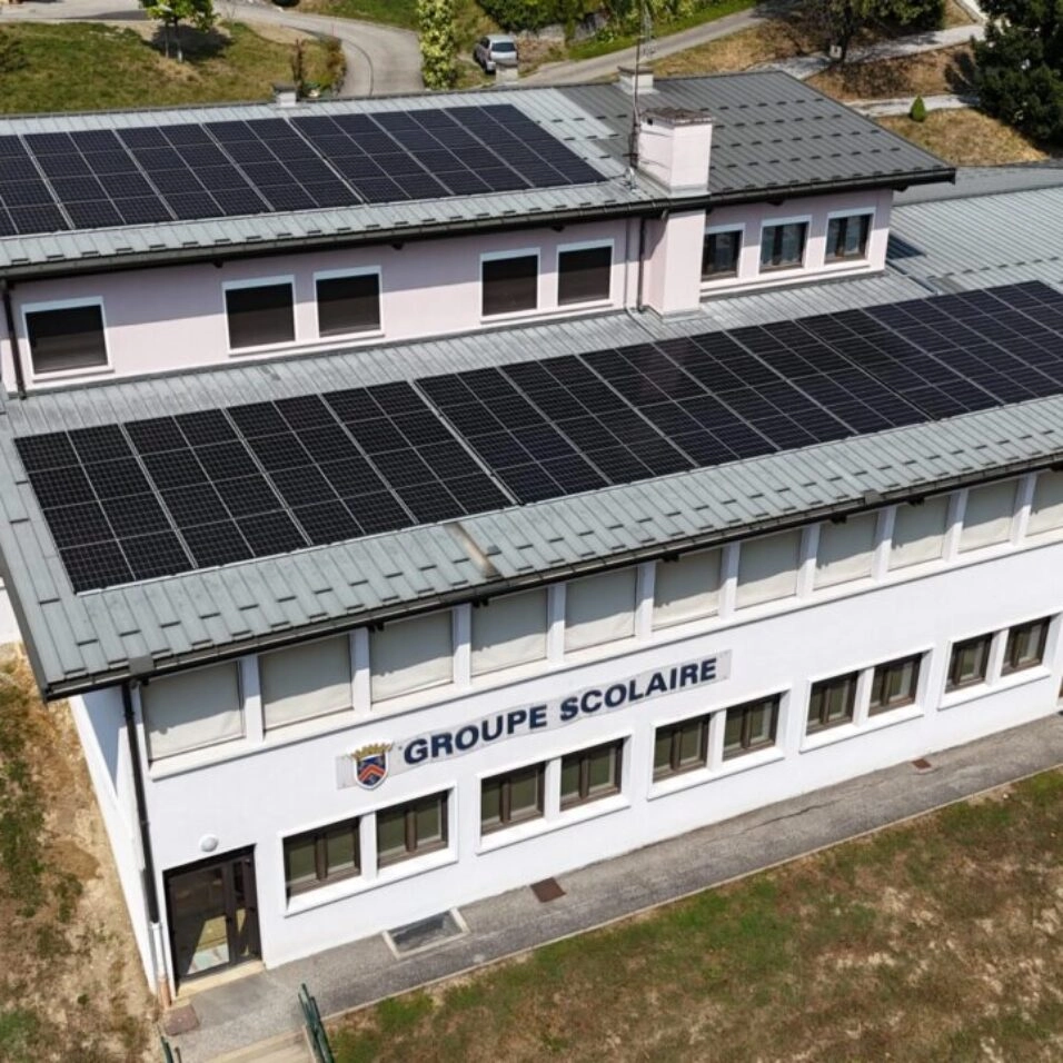 Prise de vue de drône d'un bâtiment scolaire équipé de panneaux solaire sur 2 pans de toiture exposé sud