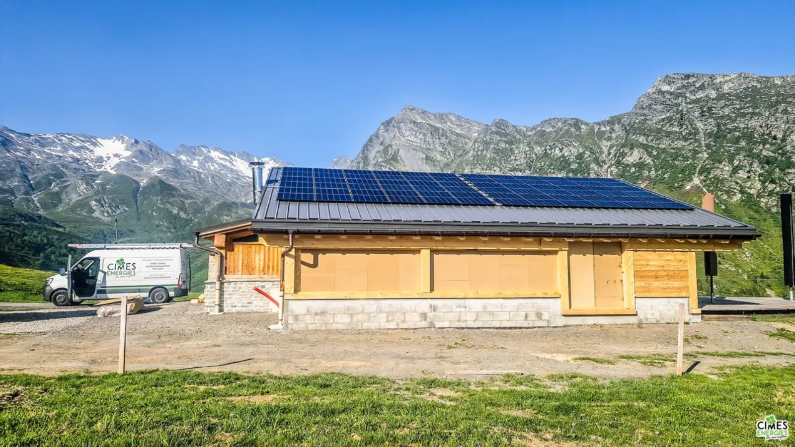 Installation solaire sur restaurant d'altitude à la Rosière, arrière-plan de montagne en été, journée ensoleillée et ciel bleu, camiion Cimes Energies garé sur le côté