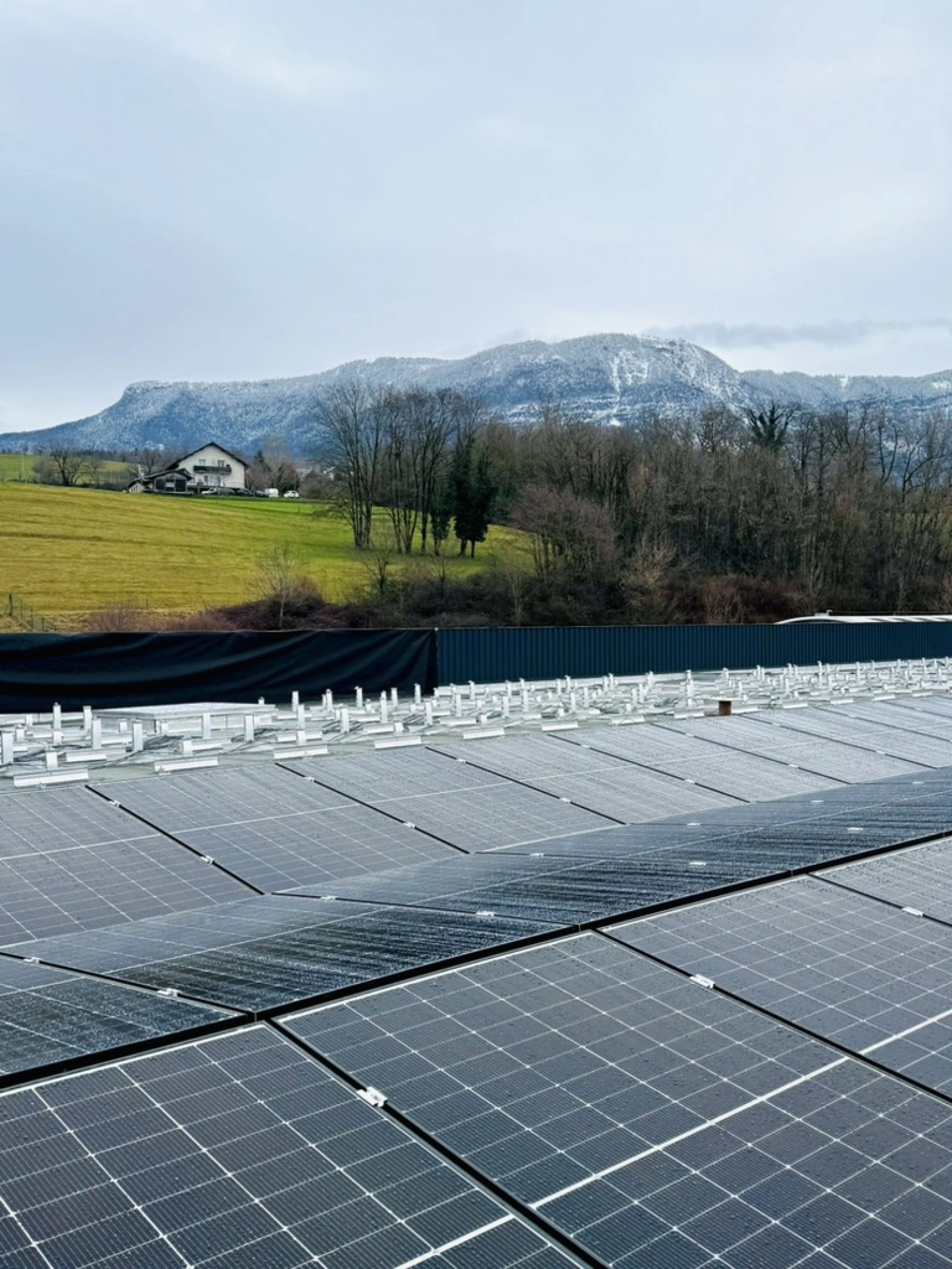 Installation photovoltaïque en autoconsommation collective pour Grolla Verre à Grésy-sur-Aix avec 286 panneaux solaires en toiture terrasse avec le Revard en arrière-plan