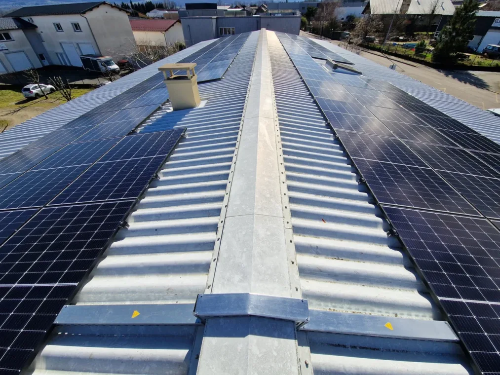 Installation solaire photovoltaïque sur la toiture d'une bâtiment d'entreprise (Allibert Trekking) en Isère, prise vue de drône en plongée
