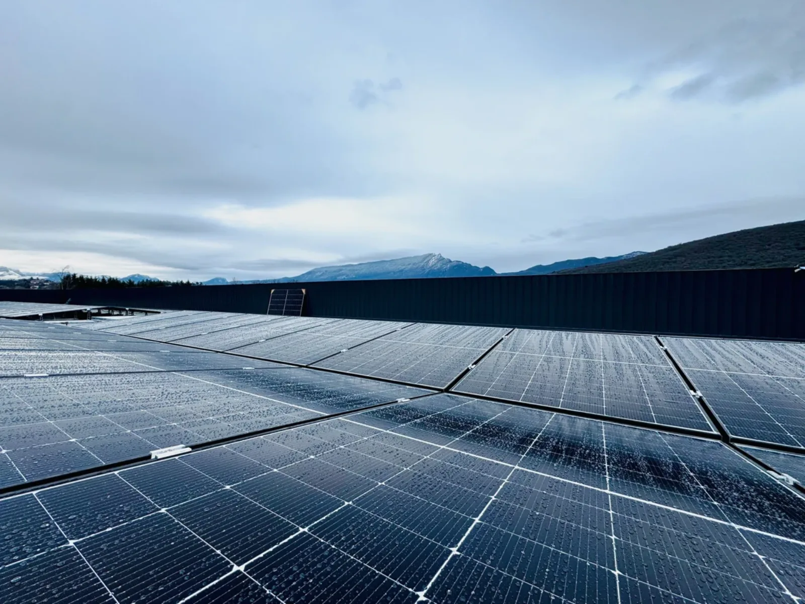 Installation solaire photovoltaïque, la Dent du Chat en arrière-plan un jour de pluie
