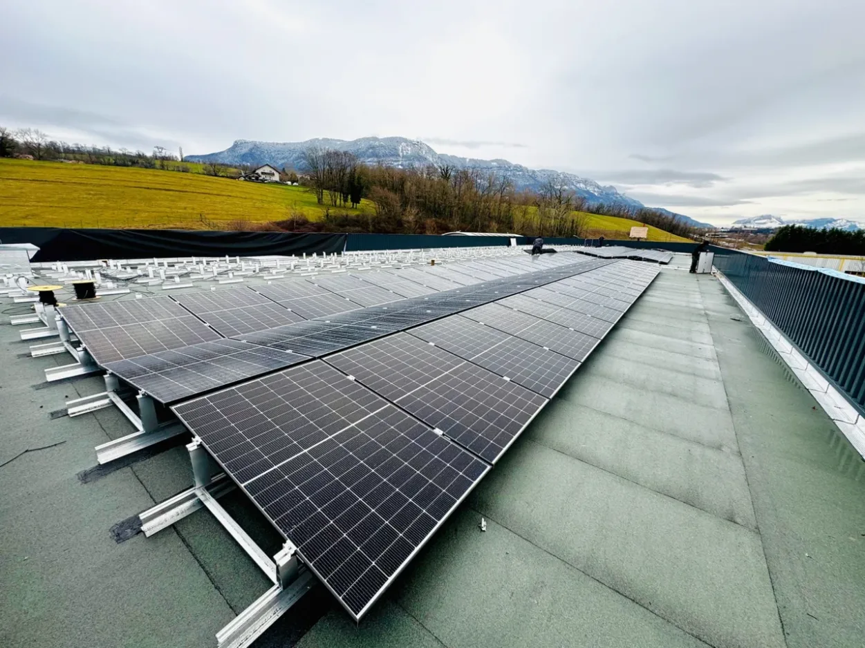 Installation solaire photovoltaïque sur la toiture de l'entreprise GROLLA Verre à Grésy-Sur-Aix, Mont Revard en arrière-plan un jour de pluie