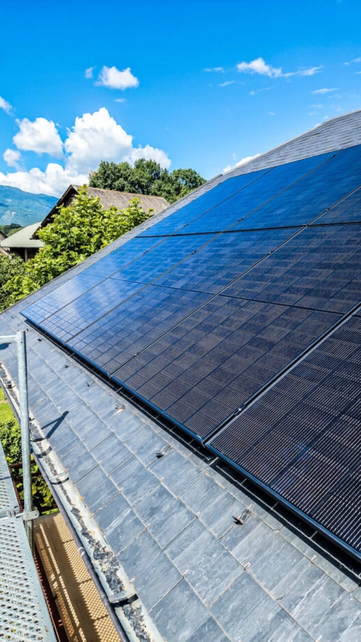 Installation solaire photovoltaïque sur toiture chez un particulier à Porte de Savoie (73), journée ensoleillée, vu en plan serré sur une partie de la toiture seulement